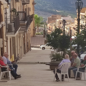 Men on a sidewalk in Sambuca di Sicilia sitting and doing sweet nothing - dolce far niente.