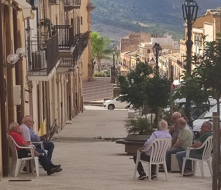 Men on a sidewalk in Sambuca di Sicilia sitting and doing sweet nothing - dolce far niente.